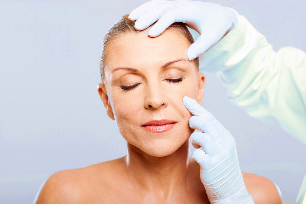 doctor examining mid age woman skin before cosmetic surgery